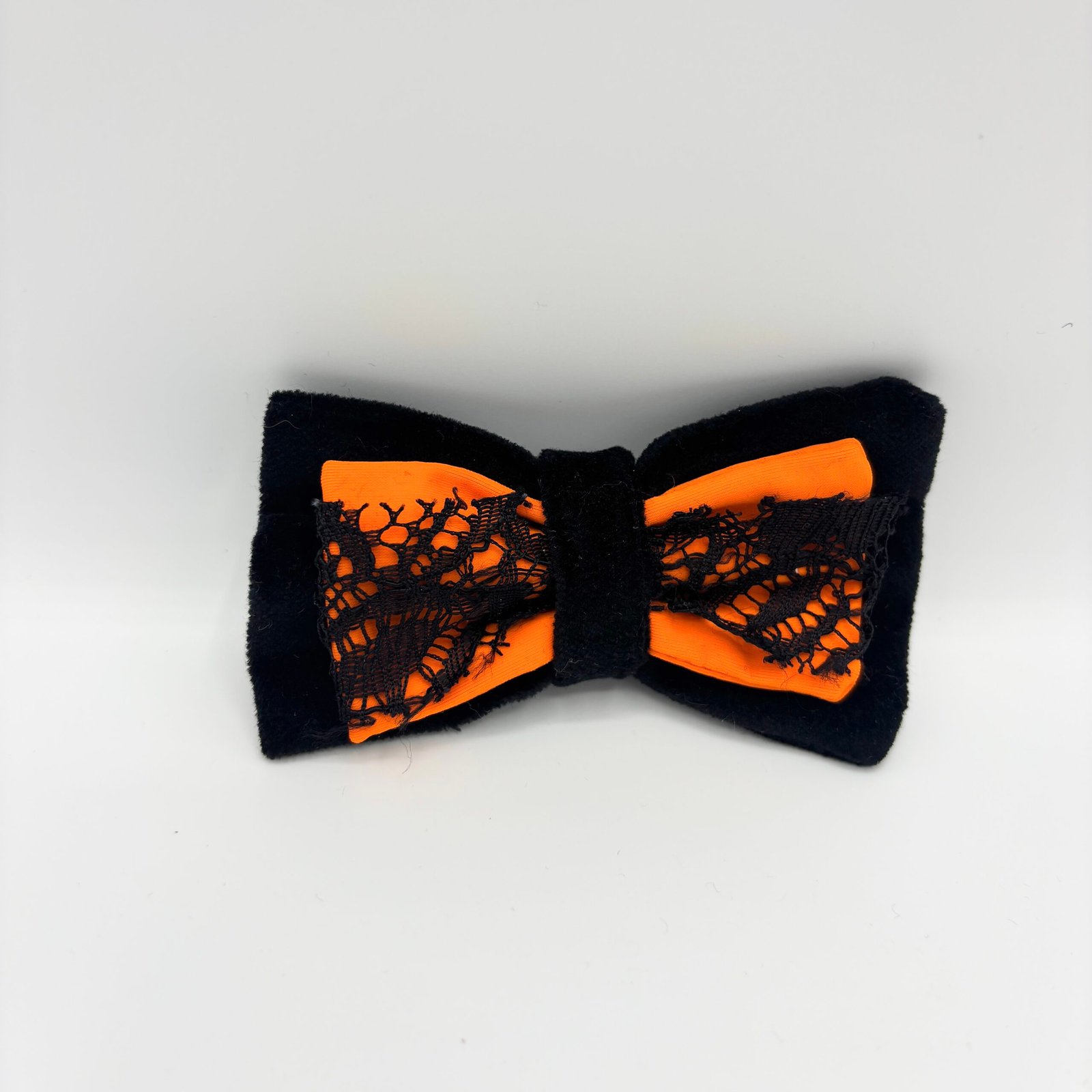 Black and orange Halloween dog bow with lace trim on a white background